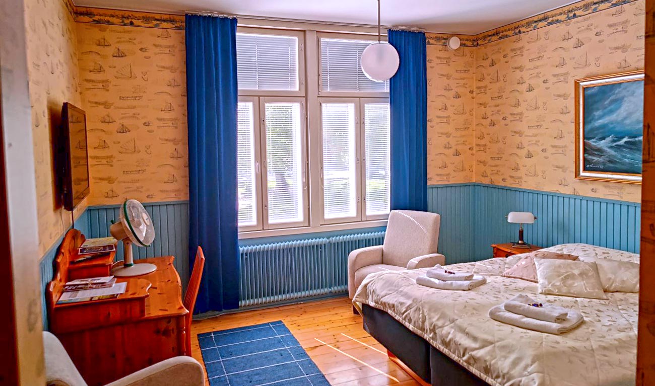 Kahden hengen huone meriaiheisella tapetilla.